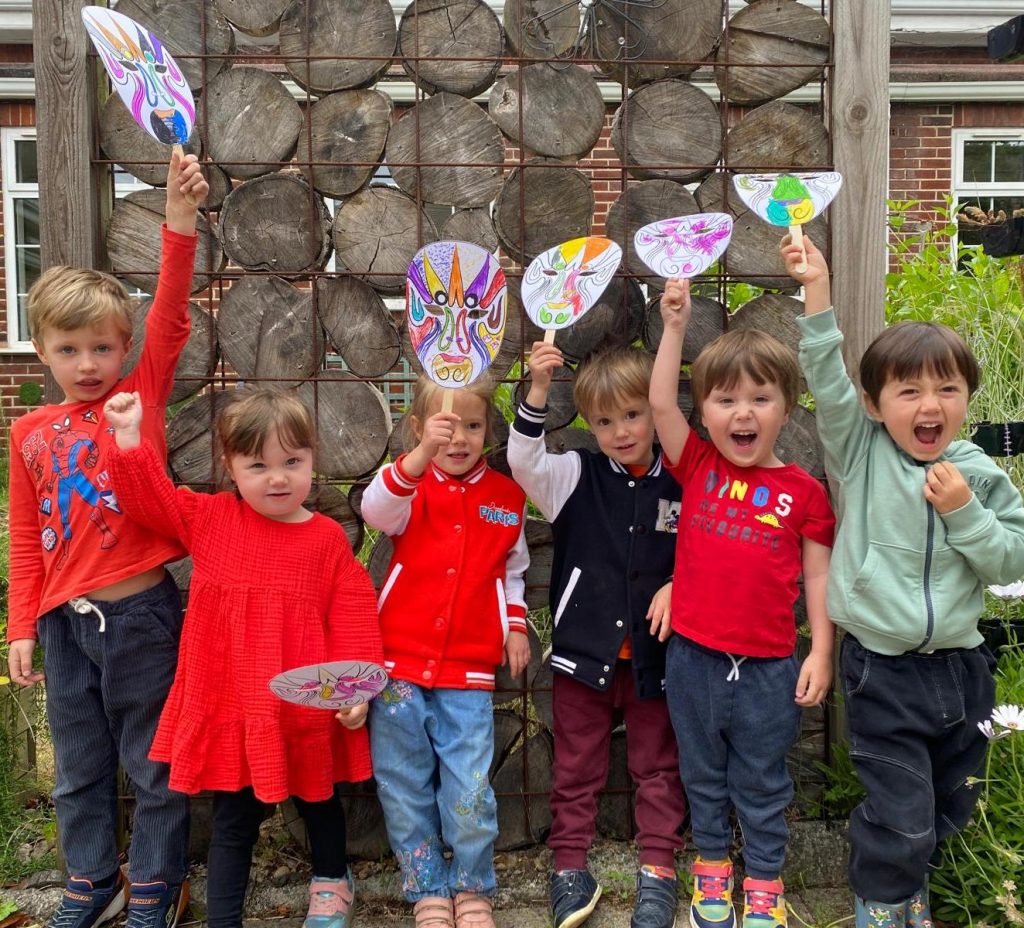 Children laugh as they wave hand made masks in the air