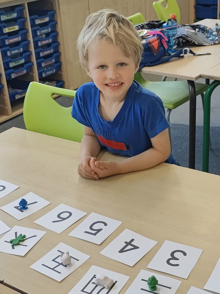 A boy sits at a desk in front of flashcards